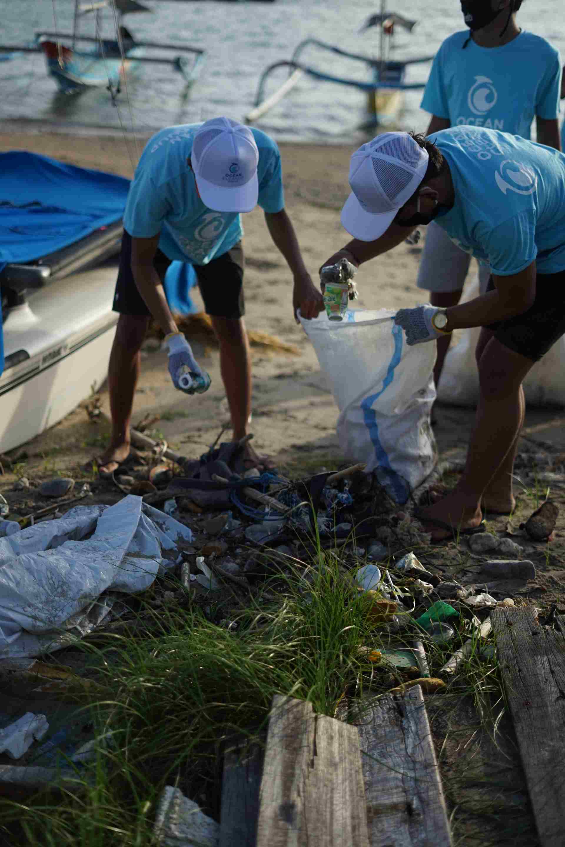 Image displaying two people picking up garbage on a beach.