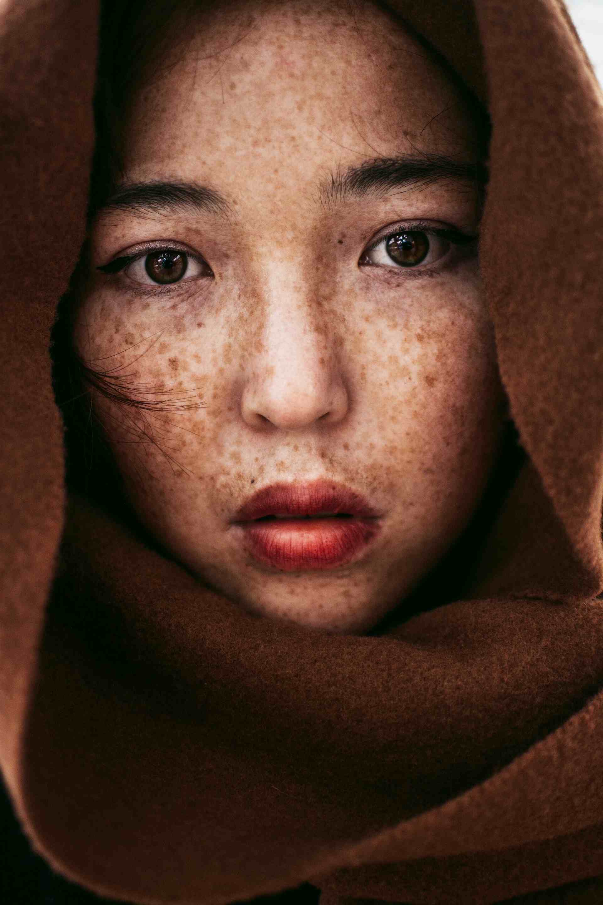 Image displaying a woman face with freckles and dark hair.