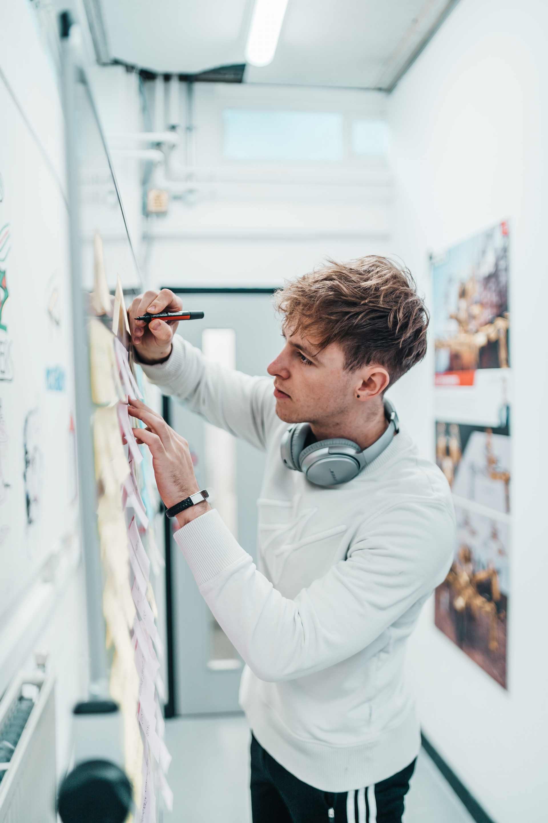 Image displaying a young man writing on a whiteboard.