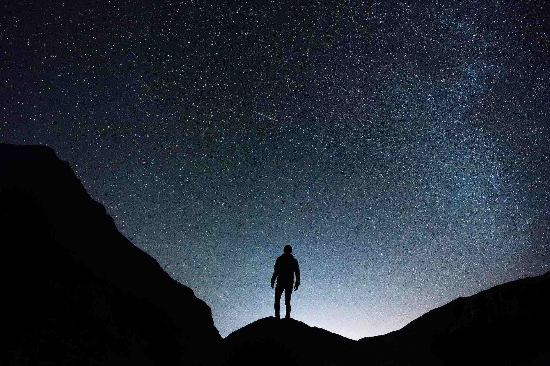 Landing page image displaying a man looking at the stars at night.